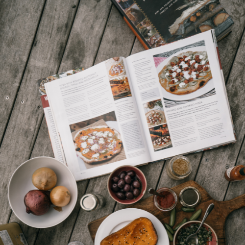 Manual abierto de manipulación de alimentos junto a ingredientes frescos en una cocina profesional.