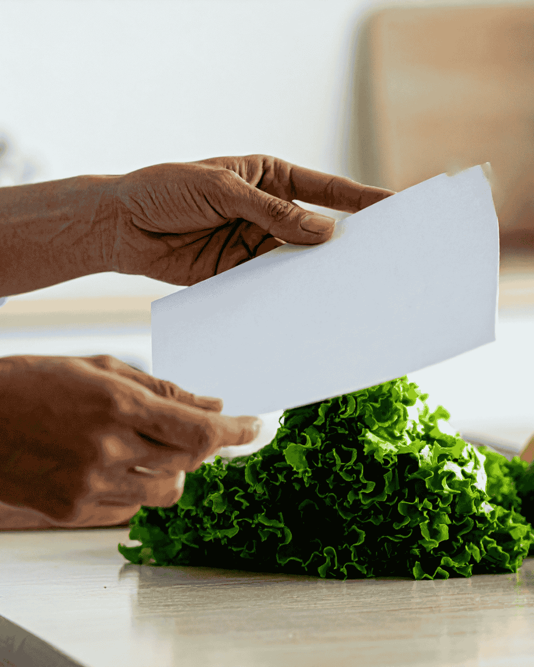 Manos de un profesional sosteniendo el examen para manipuladores de alimentos junto a vegetales frescos.